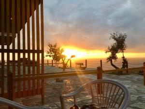 a sunset behind a fence with a chair in front at Rahoni Park & Suites in Dhërmi