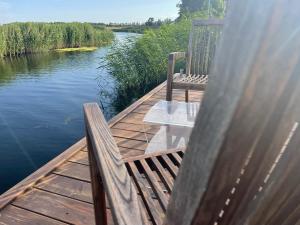 eine Holzterrasse mit einem Tisch und Stühlen auf dem Wasser in der Unterkunft Baltic Waterfront Yacht House in Świnoujście