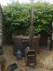 a garden with a heater and some plants at Angela's Rest Shepherds Hut with Scandi Hot Tub in Boston