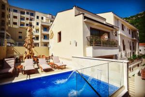 a swimming pool with chairs and a building at Vistamar Hotel & Apartments in Budva