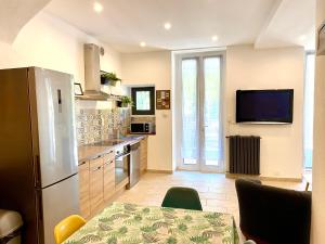 a kitchen with a refrigerator and a table and a tv at Appartement terrasse vue lac in Breil-sur-Roya