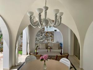 una sala da pranzo con lampadario a braccio e tavolo di Byblos Aria-The Sea Side Luxury Villa a Skala Sotiros