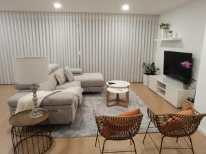 a living room with a couch and a tv and chairs at Casa de Ponte in Ponte de Lima