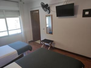 um quarto com uma cama e uma televisão na parede em Hostal Cruce em Villafranca del Bierzo