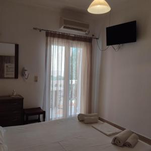 une chambre avec un lit, une télévision et une fenêtre dans l'établissement Nikolaou Thomas House, à Parga