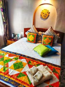 - un lit avec une couverture et des oreillers colorés dans l'établissement Mysa Maya Homestay, à Darjeeling
