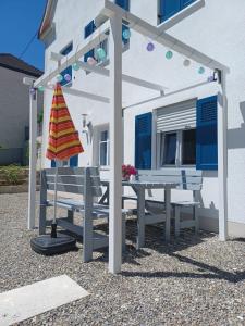 una pérgola con dos bancos y una mesa frente a un edificio en Im Stüble, en Koetz 