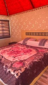 a bedroom with a large bed with pink flowers on it at Wadi Rum Nature Tours And Camp in Wadi Rum