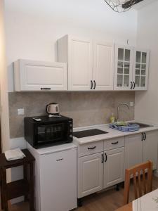 eine Küche mit weißen Schränken und einer schwarzen Mikrowelle in der Unterkunft Guest House Pikala in Goveđari