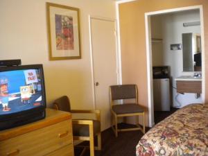 ein Hotelzimmer mit einem Fernseher auf einer Kommode und einem Bett in der Unterkunft Wasco Inn in Wasco + 19 Fotos