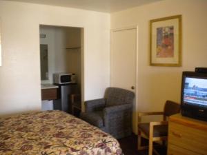 ein Hotelzimmer mit Bett, Stuhl und Fernseher in der Unterkunft Wasco Inn in Wasco