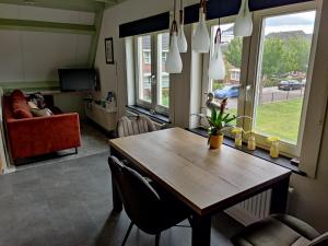 a kitchen with a wooden table and a living room at Holiday home Jong in Schagerbrug