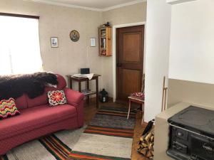 a living room with a red couch and a door at Abbis lillstuga in Norra Vallgrund +13 photos