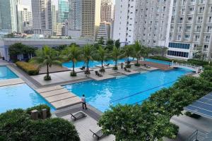 a large pool with palm trees in a city at Netflix- Destina Stays at Jazz Residences Makati, MetroManila in Manila