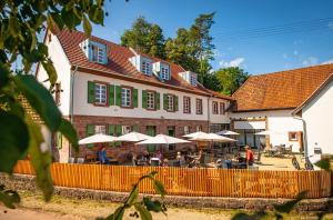 a building with tables and umbrellas in front of it at Beim Mühlenwirt in Bobenthal