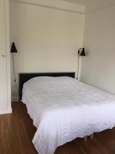 een wit bed in een kamer met 2 lampen bij Numéro 5 in Boulogne-Billancourt