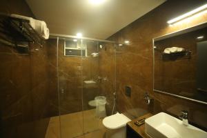 a bathroom with a shower and a toilet and a sink at Sree Fortune Grand, Tadepalli in Tādepalle +51 photos