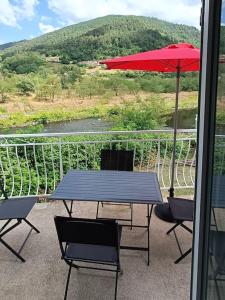 una mesa con sillas y una sombrilla en el balcón en Gite de POUNARD bord de rivière plage privée, 