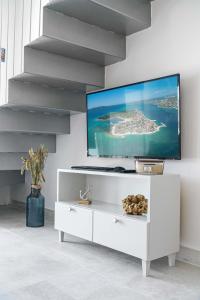 a white living room with a tv on a wall at Krapljunka, otok Krapanj in Šibenik