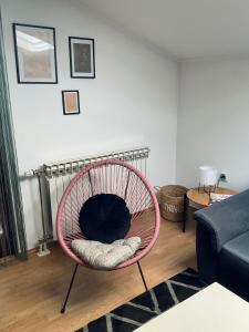 uma sala de estar com uma cadeira rosa em frente a um radiador em Apartment Camellia em Ljubuski