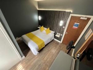 um pequeno quarto com uma cama com almofadas amarelas em dalesman hotel em Darlington