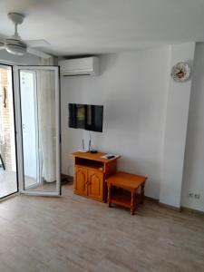 a room with a tv and a desk with a table at Apartments Las Vinas in Denia
