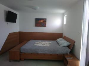 a small bedroom with a bed with a tv on the wall at Къща за гости Орлите in Ahtopol