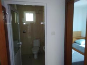 a bathroom with a toilet and a shower with a window at Къща за гости Орлите in Ahtopol