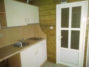 a kitchen with white cabinets and a sink and a door at Къща за гости Орлите in Ahtopol