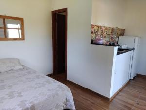 1 dormitorio con 1 cama y nevera blanca en Pousada e Cervejaria Amor in Malte en Lavrinhas
