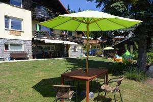 a table with a green umbrella in a yard at Pension Arabela in Harrachov