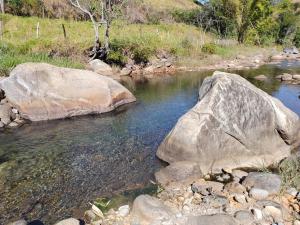 een rivier met twee grote rotsen in het water bij Pousada e Cervejaria Amor in Malte in Lavrinhas