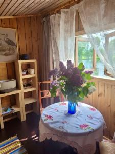 un jarrón de flores sobre una mesa con una ventana en Laivu māja uz Alūksnes ezera/ Boat house on a Lake, en Alūksne