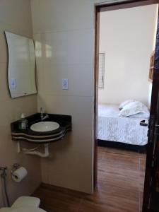 a bathroom with a sink and a bed at Pousada e Cervejaria Amor in Malte in Lavrinhas