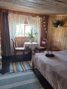 1 dormitorio con mesa, sillas y ventana en Laivu māja uz Alūksnes ezera/ Boat house on a Lake en Alūksne