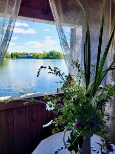 um vaso de flores numa janela com vista para a água em Laivu māja uz Alūksnes ezera/ Boat house on a Lake em Alūksne