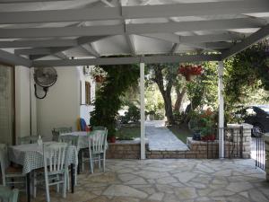 un patio con tavoli e sedie sotto un pergolato bianco di Hotel Akropolis a Sivota