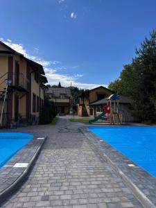 ein Pool mit Spielplatz neben einigen Häusern in der Unterkunft Sadyba Magnat Hotel in Dilyatyn