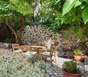 a table and chairs in a garden with a stone wall at Molivos Tower in Mythimna