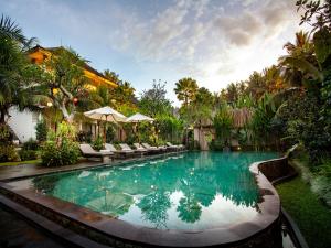 a swimming pool in a yard with chairs and trees at The Kalyana Ubud Resort in Ubud