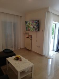 ein Wohnzimmer mit einem Tisch und einem TV an der Wand in der Unterkunft Apartment by the Sea, Peraia Thessaloniki in Peraia