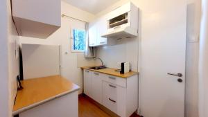 a small kitchen with white cabinets and a white refrigerator at Little Troll House 1 in Chrissi Akti