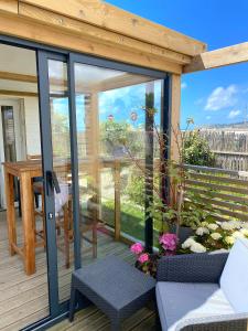 a screened in porch with glass doors and flowers at La Villa plein vent "La Cabine" vue mer in Barneville-Carteret