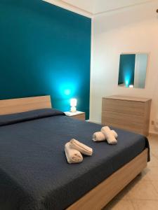 - 2 serviettes sur un lit avec un mur bleu dans l'établissement Sofi House, à Santo Stefano di Camastra