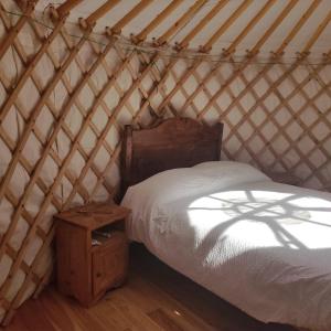 een slaapkamer met een bed en een houten nachtkastje bij Glamping la Cascina d'Orleans in Saint-Pierre