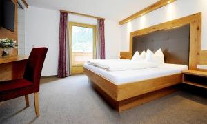 1 dormitorio con cama, escritorio y ventana en Apart Christine - Silvrettacard-Sommer inklusive, en Galtür