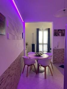 ein Esszimmer mit violetter Beleuchtung sowie einem Tisch und Stühlen in der Unterkunft Ulivo Apartment in Trapani