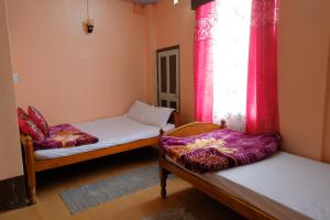 a room with two beds and a window with red curtains at Down Town Homestay in Kurseong