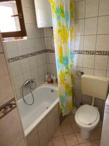 a bathroom with a tub and a toilet and a shower curtain at Apartment Cuni in Mostar +9 photos
