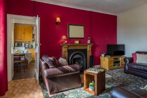 a living room with red walls and a fireplace at Shemore Farm Holiday Cottage in Luss